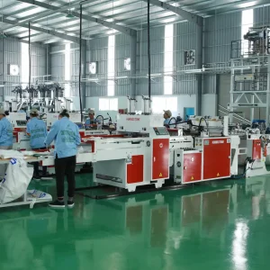 Workers operating advanced plastic bag manufacturing equipment at Hanoi Plastic Bags Manufacturing JSC in Vietnam